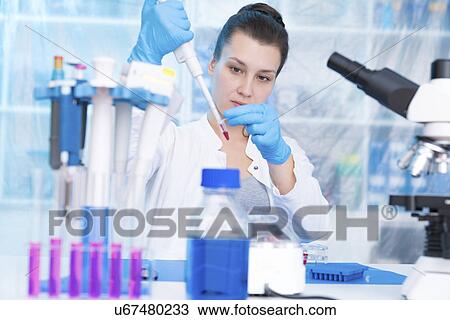 Stock Image - Scientist using pipette in laboratory. Fotosearch