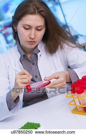 Stock Image - Scientist writing on test tube. Fotosearch