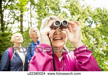 Picture - Senior woman looking through binoculars. Fotosearch