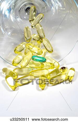 Stock Image - Several yellow gelatin pills with one unique green one on white background. Fotosearch
