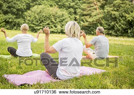 Three people doing yoga in field View Large Photo Image Stock Photograph - Three people doing yoga in field. Fotosearch