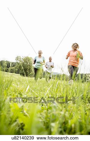 Three people running in field View Large Photo Image Stock Photo - Three people running in field. Fotosearch
