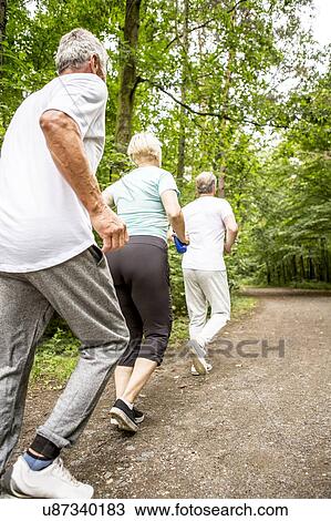 Stock Image - Three people running on track in woods. Fotosearch