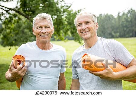 Stock Photograph - Two men with yoga mats, smiling. Fotosearch