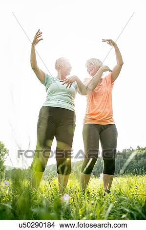 Picture - Two women exercising with arms raised. Fotosearch