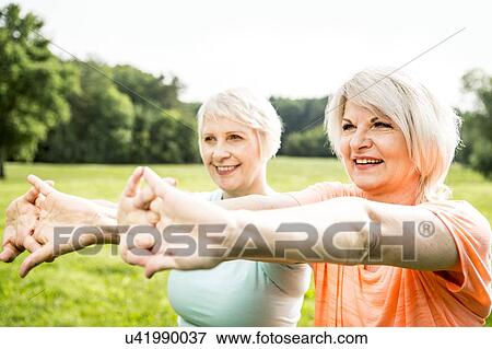Stock Photo - Two women exercising with arms outstretched. Fotosearch