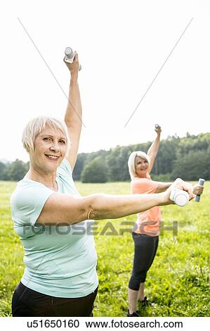 Stock Image - Two women exercising with hand weights. Fotosearch