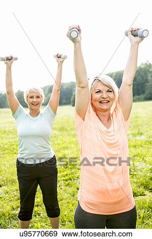 Two women exercising with hand weights View Large Photo Image Stock Photo - Two women exercising with hand weights. Fotosearch