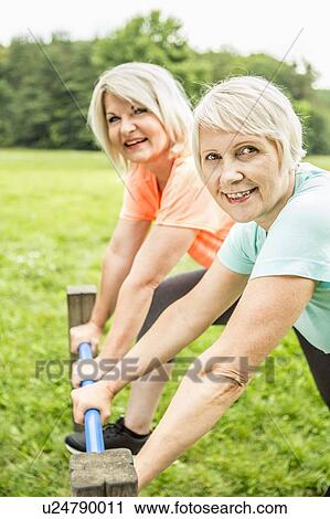 Two women smiling towards camera holding railing View Large Photo Image Stock Image - Two women smiling towards camera holding railing. Fotosearch