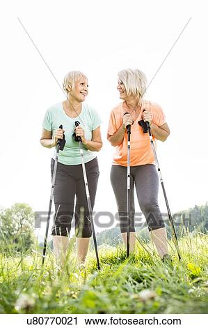 Stock Image - Two women with walking poles. Fotosearch