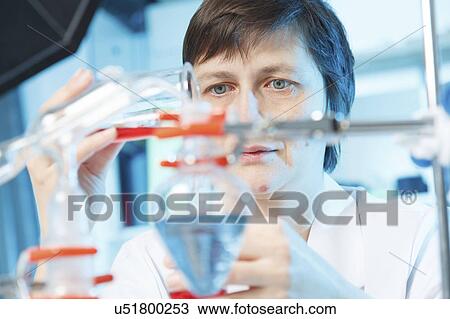 Stock Image - Woman doing experiment in chemical laboratory. Fotosearch