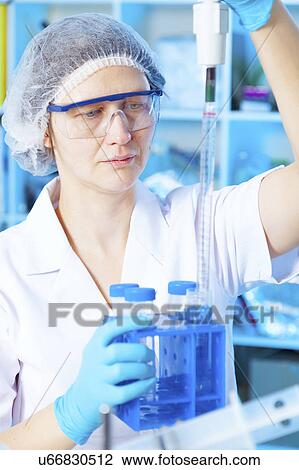 Stock Image - Woman measuring liquid in chemical laboratory. Fotosearch