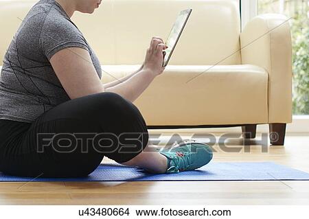 Picture - Woman sitting on floor using digital tablet. Fotosearch