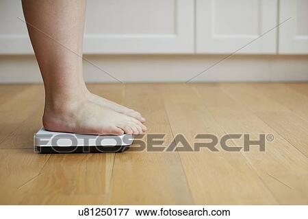 Woman standing on weighing scales View Large Photo Image Stock Photo - Woman standing on weighing scales. Fotosearch