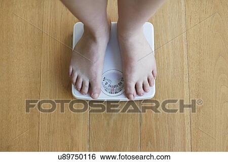 Woman standing on weighing scales View Large Photo Image Stock Photograph - Woman standing on weighing scales. Fotosearch