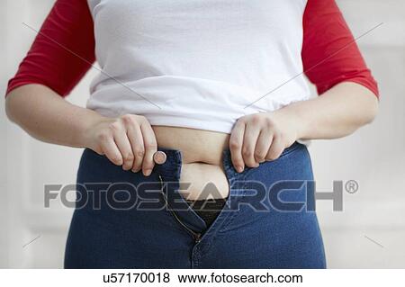 Stock Photo - Woman trying to button jeans over tummy. Fotosearch