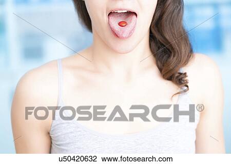 Stock Image - Woman with red pill on tongue. Fotosearch