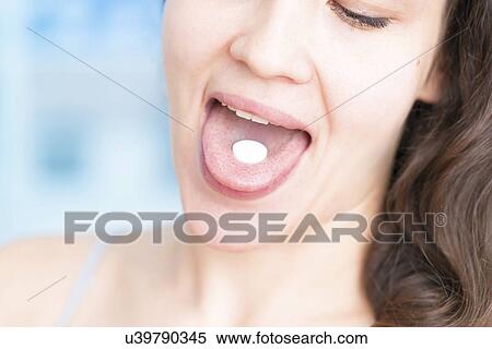 Stock Photography - Woman with white pill on tongue. Fotosearch