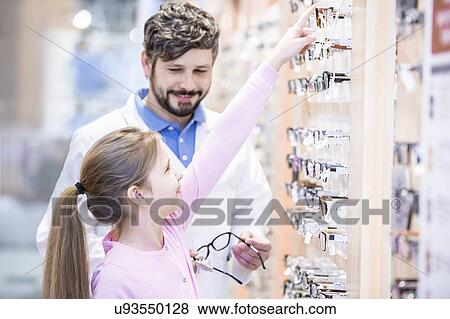 Young girl choosing glasses with optometrist View Large Photo Image Stock Photo - Young girl choosing glasses with optometrist. Fotosearch
