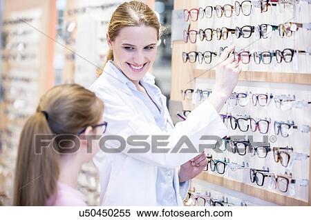 Stock Photography - Young girl choosing glasses with optometrist. Fotosearch