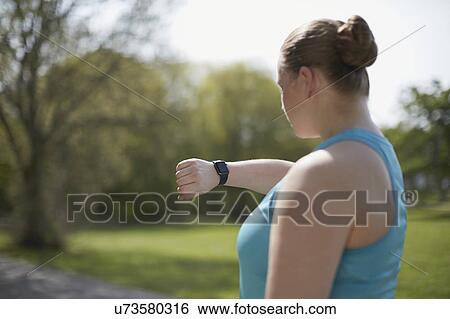 Stock Photograph - Young woman checking sports watch. Fotosearch