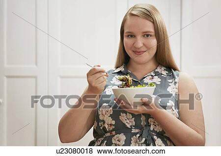 Young woman eating bowl of salad View Large Photo Image Stock Photo - Young woman eating bowl of salad. Fotosearch