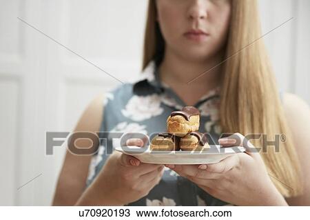 Young woman holding plate of chocolate eclairs View Large Photo Image Stock Image - Young woman holding plate of chocolate eclairs. Fotosearch