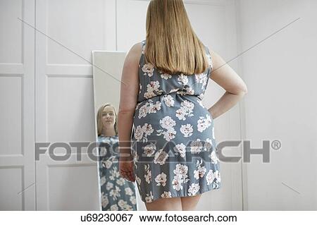 Young woman looking at reflection in mirror View Large Photo Image Stock Photo - Young woman looking at reflection in mirror. Fotosearch