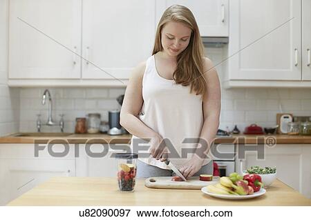 Stock Photo - Young woman preparing healthy food in kitchen. Fotosearch