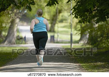 Stock Image - Young woman running on path, rear view. Fotosearch