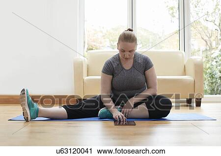 Young woman sitting on floor using digital tablet View Large Photo Image Stock Image - Young woman sitting on floor using digital tablet. Fotosearch