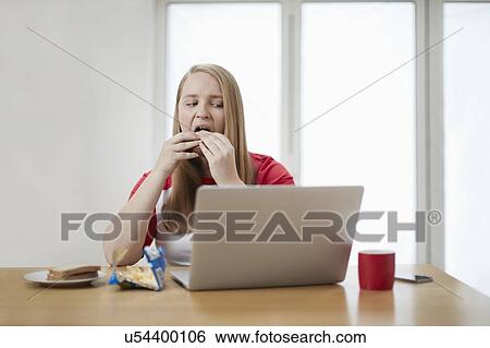 Young woman with laptop eating sandwich View Large Photo Image Stock Photograph - Young woman with laptop eating sandwich. Fotosearch