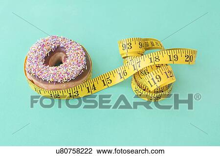 Stock Image - Doughnut and tape measure. Fotosearch