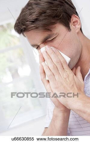 Stock Photography - Man blowing nose on tissue. Fotosearch