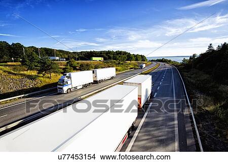 Picture - Trucks driving on a scenic highway. Fotosearch