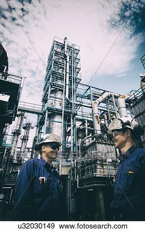 Stock Photo - Two industrial workers on oil and gas refinery. Fotosearch