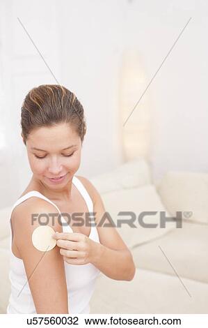 Stock Image - Woman applying nicotine path to arm. Fotosearch