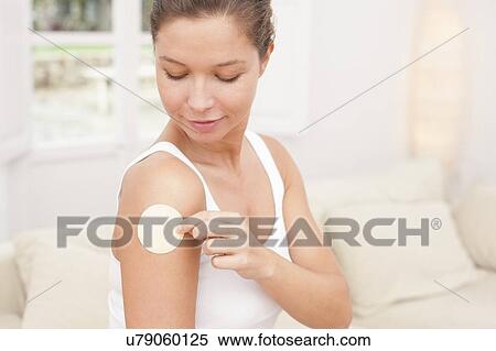 Stock Photography - Woman applying nicotine path to arm. Fotosearch