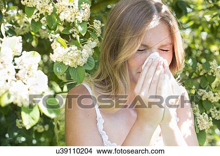 Picture - Woman blowing nose on tissue. Fotosearch