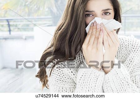 Picture - Woman blowing nose on tissue. Fotosearch