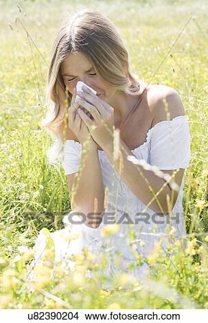 Picture - Woman blowing nose on tissue. Fotosearch