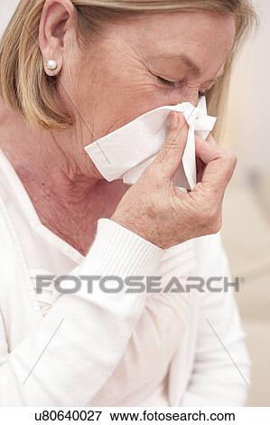 Stock Photo - Woman blowing nose on tissue. Fotosearch