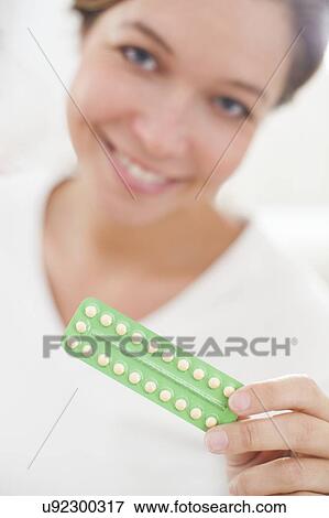 Stock Photo - Woman holding contraceptive pills. Fotosearch