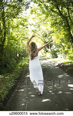 Stock Photography - Woman in long white dress on country lane. Fotosearch