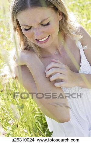 Woman in meadow scratching arm View Large Photo Image Picture - Woman in meadow scratching arm. Fotosearch