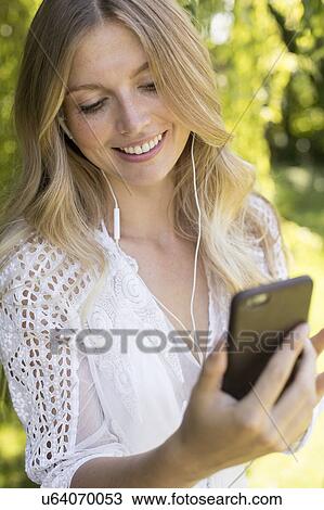Stock Image - Woman listening to music on smartphone. Fotosearch