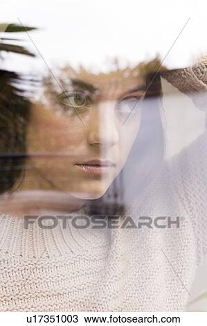 Stock Image - Woman looking away, view through reflective glass. Fotosearch
