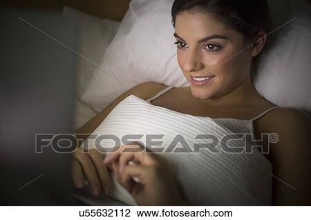 Woman lying in bed watching laptop View Large Photo Image Stock Image - Woman lying in bed watching laptop. Fotosearch