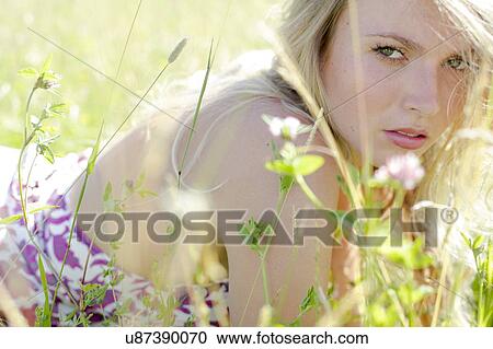 Stock Image - Woman lying in meadow with wild flowers. Fotosearch