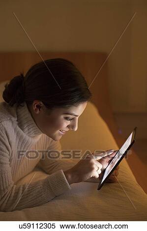 Woman lying on bed with digital tablet View Large Photo Image Stock Photography - Woman lying on bed with digital tablet. Fotosearch